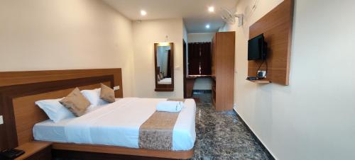 a hotel room with a bed and a television at Sanjose Residency in Virajpet