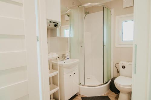 a white bathroom with a shower and a toilet at LUXURY CAMP - 150 m od Suntago Park in Grabce-Towarzystwo