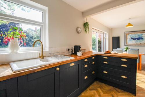 eine Küche mit schwarzen Schränken, einem Waschbecken und einem Fenster in der Unterkunft Elegant 3-Bed Home, West Bridgford & Large Garden in Nottingham