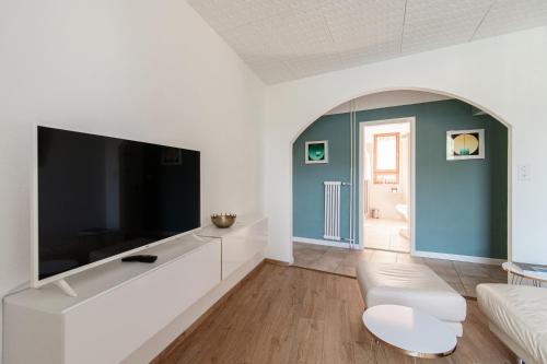 sala de estar con TV grande y sofá en Casa Celeste by Quokka 360 - flat with a view of Lake Lugano, en Caslano