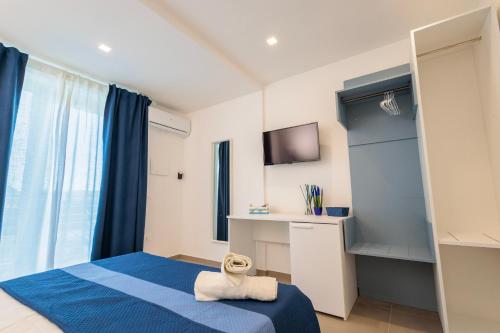 um quarto com uma cama azul e uma televisão em Orizzonte Mare Panoramic Rooms em Agropoli
