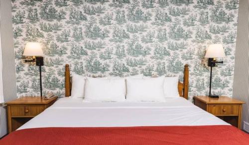 a bedroom with a white bed with two lamps at Williamsburg Woodlands Hotel & Suites, an official Colonial Williamsburg Hotel in Williamsburg