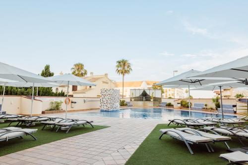 una piscina con tumbonas y sombrillas en Hotel Las Gaviotas, en La Manga del Mar Menor