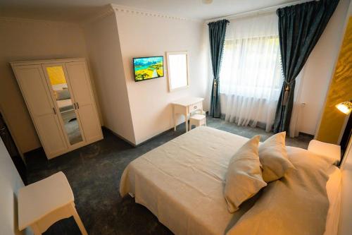 - une chambre avec un grand lit blanc et une fenêtre dans l'établissement Pensiunea Alessia Soveja, à Soveja