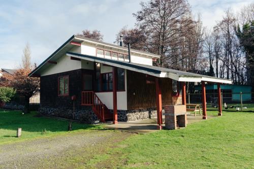 una pequeña casa con un porche en un campo en Hotel Terrazas del Lago en Puerto Varas