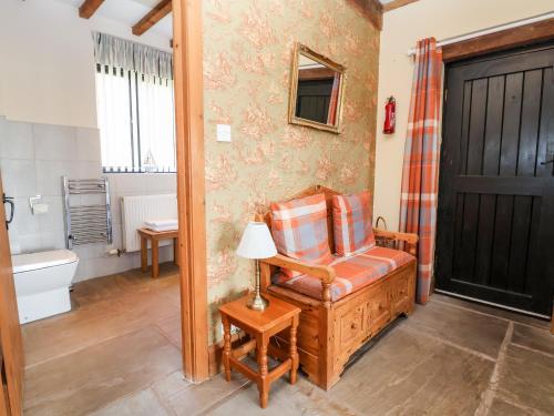 a living room with a chair and a bathroom at The Old Carthouse in Nantwich