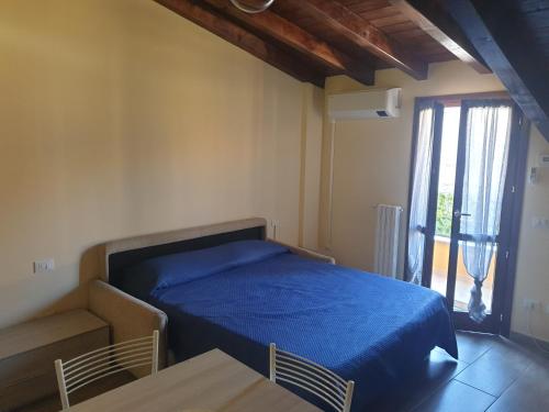 una camera con letto blu, tavolo e finestra di Monolocale Seveso - Affitti brevi - Residence a Seveso