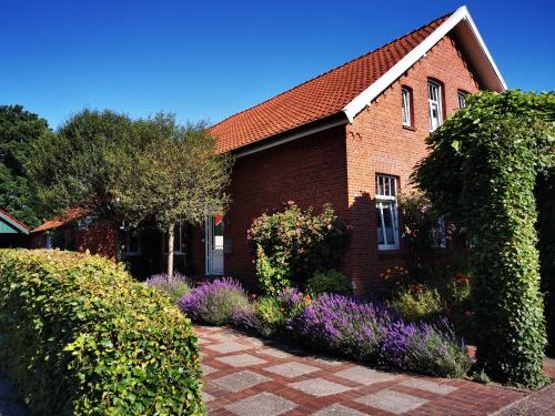 a red brick house with flowers in front of it at Ferienwohnung Heckmann, 95138 in Rhauderfehn