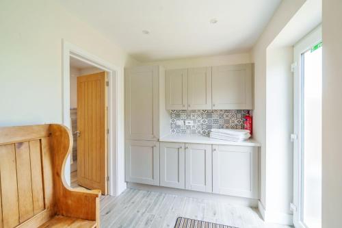 uma cozinha com armários brancos e piso em madeira em The Cow Shed em Sherborne