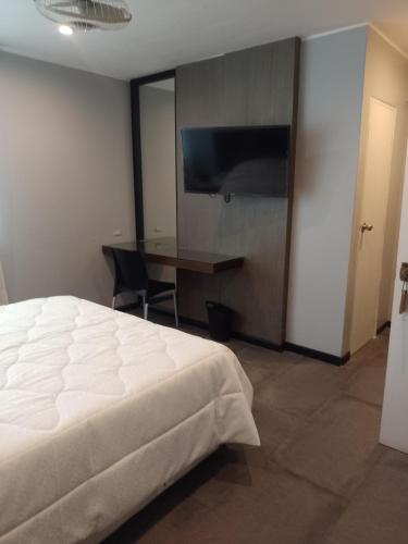 Dormitorio con cama, escritorio y TV en Hotel Continental, en Barranca