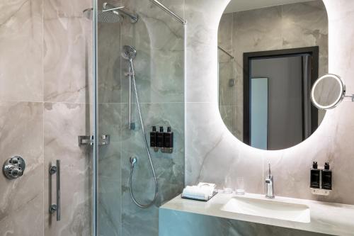 a bathroom with a shower and a sink and a mirror at The Marmorosch Bucharest, Autograph Collection in Bucharest