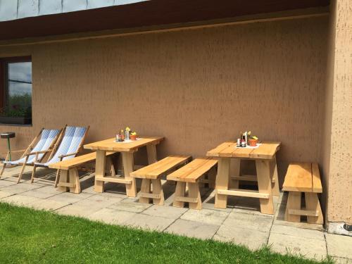 a wooden picnic table and chairs next to a wall at Pension Horske Zatisi in Horni Misecky