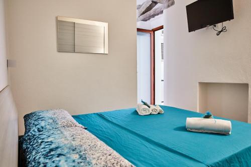 a bedroom with a bed with blue sheets and a television at House Angelo La Punzesa in Santa Teresa Gallura