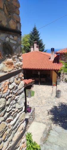 a stone building with a red roof and a stone patio at Kastania Gi in Palaios Panteleimon