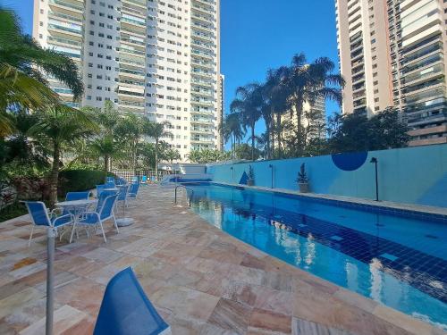 Una piscina con sillas y edificios azules. en Quarto privativo em Apto Barra com Vista - com anfitrião, en Río de Janeiro