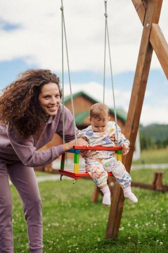 a woman holding a baby on a swing at Eco Village & Chalets Green Heaven in Mojkovac