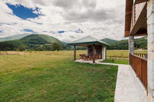a gazebo on the side of a house in a field at Eco Village & Chalets Green Heaven in Mojkovac