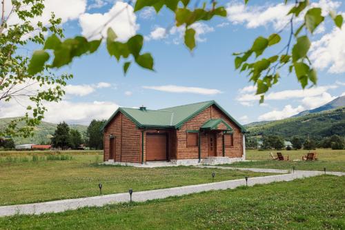 a small building in a field with mountains in the background at Eco Village & Chalets Green Heaven in Mojkovac