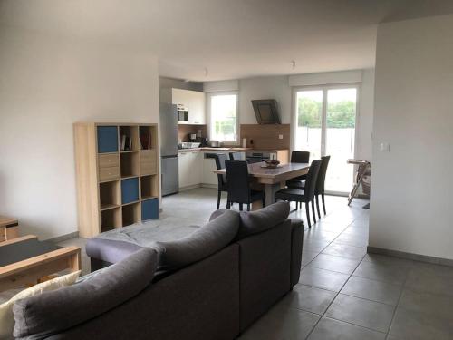 a living room with a couch and a table with chairs at Maison les coquelicots in Garennes-sur-Eure