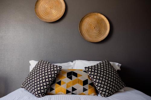 a bed with pillows and two hats on a wall at Logis Le P'tit Rouillon au Rythme de la Meuse in Annevoie-Rouillon