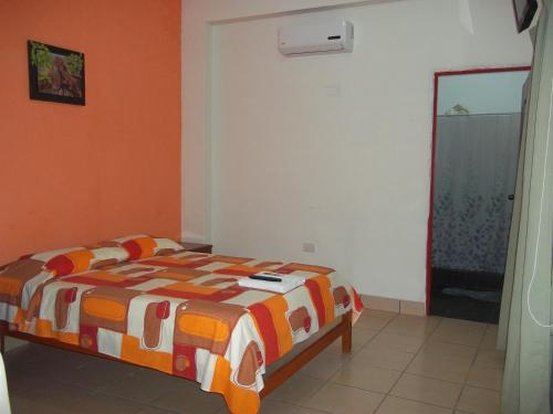 1 dormitorio con cama y pared de color naranja en Casa Linda II, en Iquitos