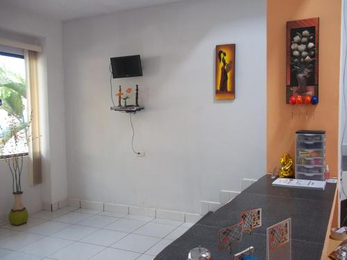 a living room with a table and a tv on the wall at Casa Linda II in Iquitos