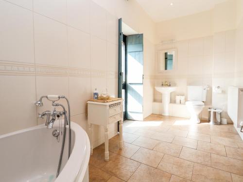a bathroom with a tub and a toilet and a sink at Cromwells Manor in Nantwich