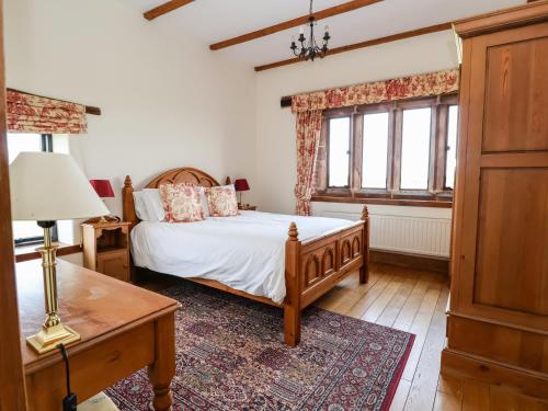 a bedroom with a bed and a table and windows at Cromwells Manor in Nantwich