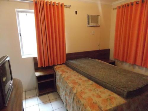 1 dormitorio con 2 camas, cortinas de color naranja y ventana en Diroma Internacional Acqua Park, en Caldas Novas