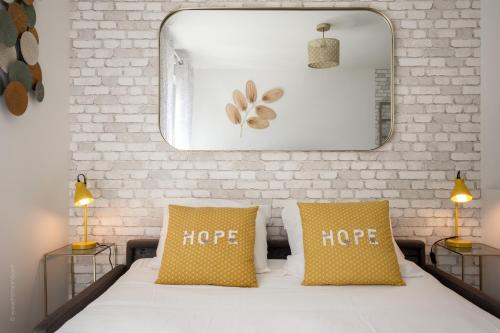 a white bed with two yellow pillows and a mirror at L'Atelier des Rêves by Plaza proche Disneyland in Montévrain