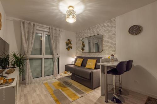 a living room with a couch and a table at L'Atelier des Rêves by Plaza proche Disneyland in Montévrain
