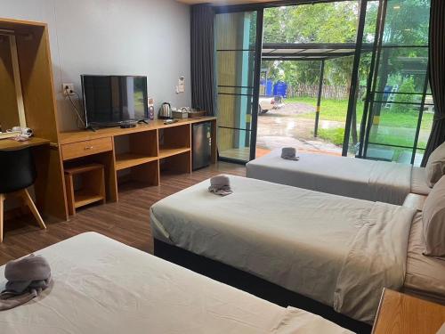 a room with two beds and a desk with a television at พบรักรีสอร์ท Pobruk resort in Tha Bo