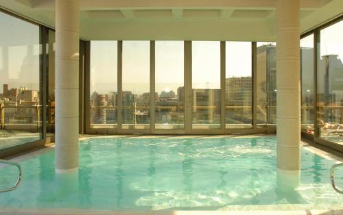 a large swimming pool in a building with windows at Plaza El Bosque Ebro in Santiago