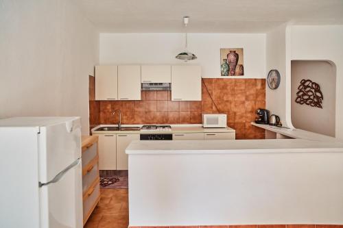 a kitchen with white cabinets and a white refrigerator at House Giuà La Punzesa in Santa Teresa Gallura