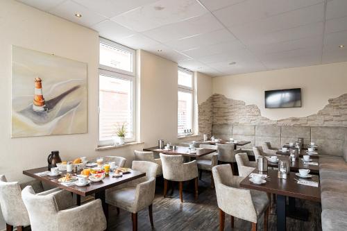 Hotel Banter Hof في فيلهلمسهافن: مطعم فيه طاولات وكراسي في الغرفة