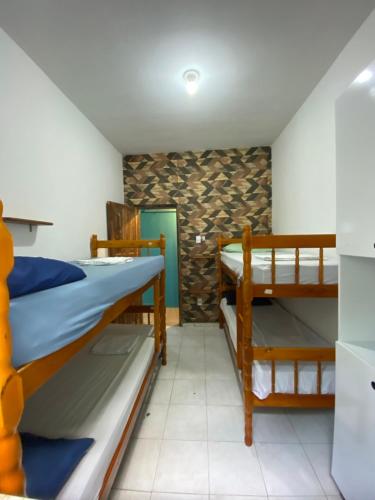 a room with two bunk beds and a refrigerator at La Casa Hostel in Arraial do Cabo