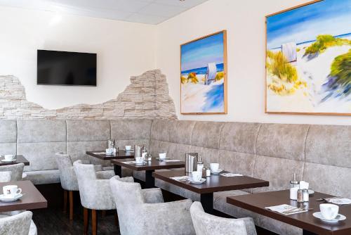 ein Restaurant mit Tischen und Stühlen und einem Flachbild-TV in der Unterkunft Hotel Banter Hof in Wilhelmshaven
