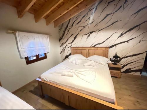 a bedroom with a large bed with a stone wall at Bujtina Te Xhako in Përmet