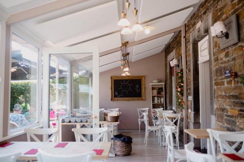 a restaurant with white chairs and tables and a brick wall at Logis Le P'tit Rouillon au Rythme de la Meuse in Annevoie-Rouillon