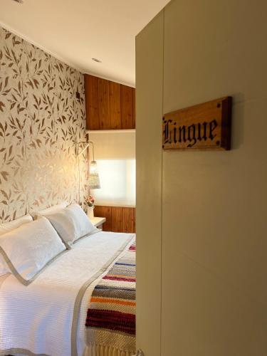 a bedroom with a bed with a wooden sign on the wall at Hotel Boutique Casa&Alma in Puerto Varas
