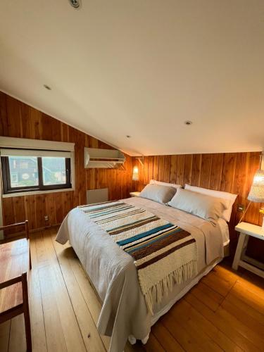 a bedroom with a large bed and wooden walls at Hotel Boutique Casa&Alma in Puerto Varas