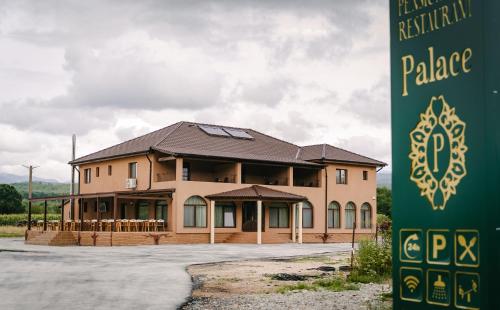 a large building with a sign in front of it at PENSIUNE-RESTAURANT Palace in Cărpinet