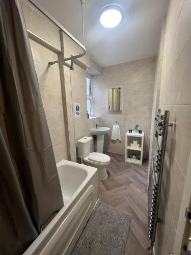 a bathroom with a tub and a toilet and a sink at Stunning Wembley Stadium Flat in London