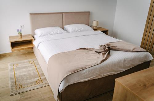 a bedroom with a large bed with white sheets at PENSIUNE-RESTAURANT Palace in Cărpinet