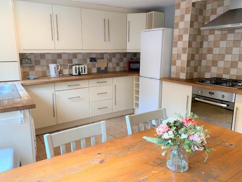 a kitchen with a wooden table with a vase of flowers on it at Lovely Victorian House near Liverpool Centre in Liverpool