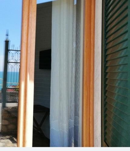 a window with a view of the ocean and a lighthouse at Apartments Tellaro in Tellaro