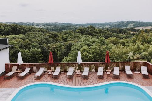 a pool with chairs and umbrellas on a deck at MY HOME ADDL in Štrigova