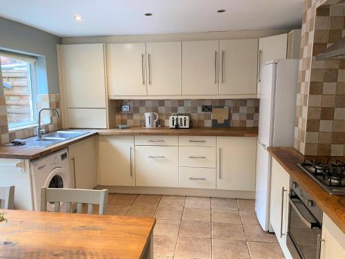 a kitchen with white cabinets and a washer and dryer at Lovely Victorian House near Liverpool Centre in Liverpool