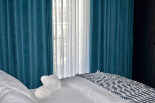 a bedroom with a bed with blue curtains and a window at Olive House in Golem