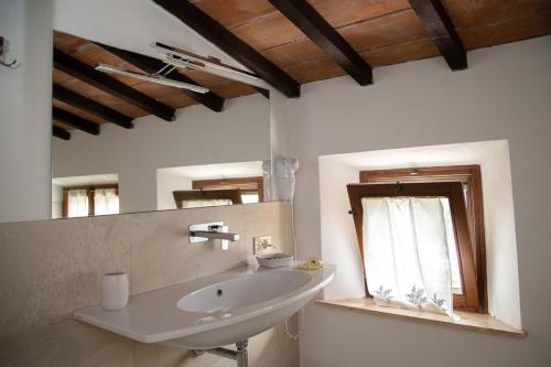 a white bathroom with a sink and a window at Locanda Il Porcellum in Bagno Vignoni
